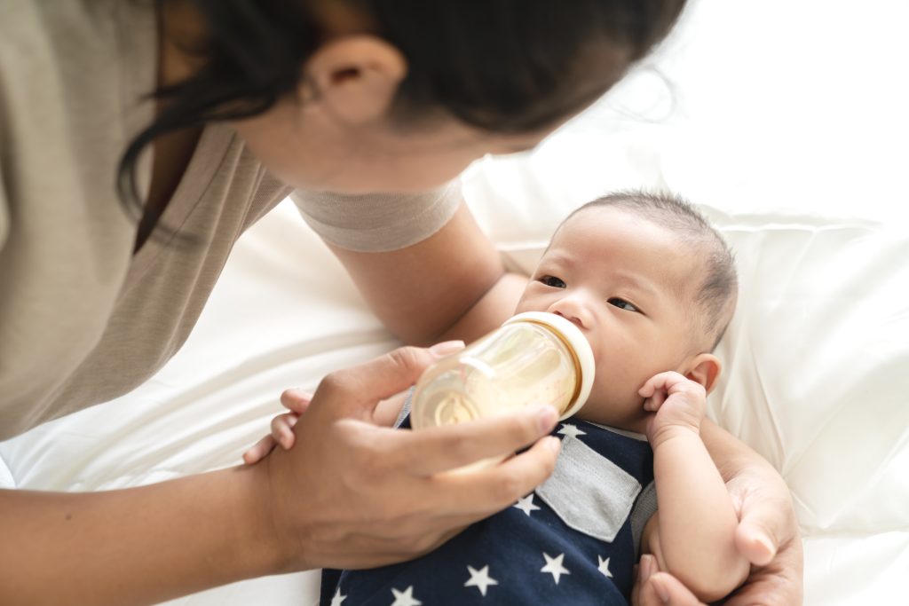 A mother bottlefeeding her newborn. Mothers dealing with newborns can benefit from FDW transfer, allowing them to get an FDW in the household immediately.