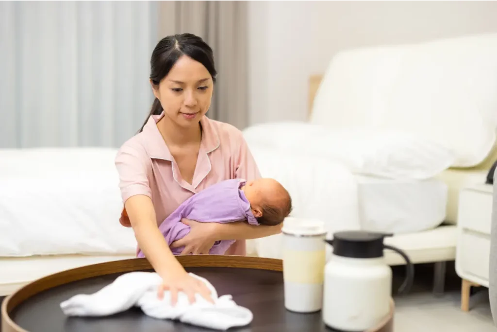 a confinement nanny in singapore taking care of a newly born baby while wiping the table