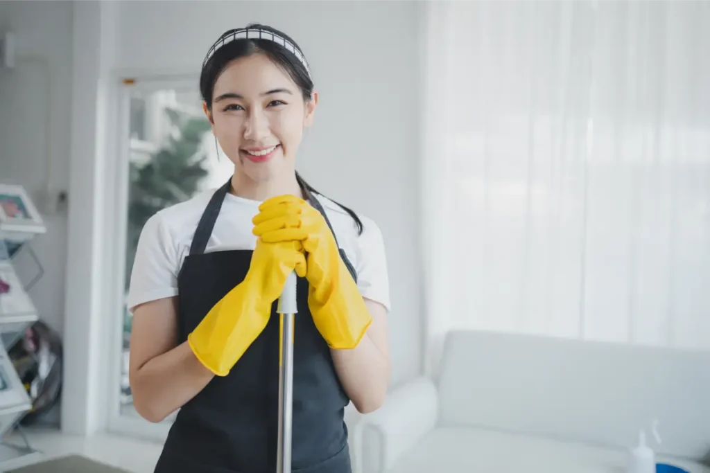 a transfer maid, hired through an agency in Singapore, holding a mop