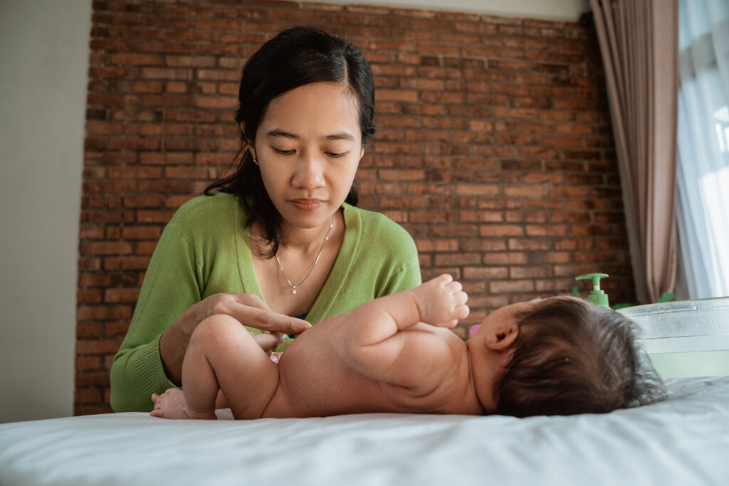 Caregiver changing a newborn's nappy during a home care routine.