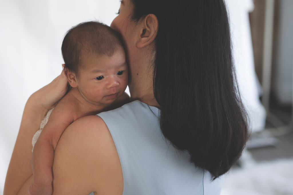 Confinement nanny holding and comforting a newborn baby during a home care visit.